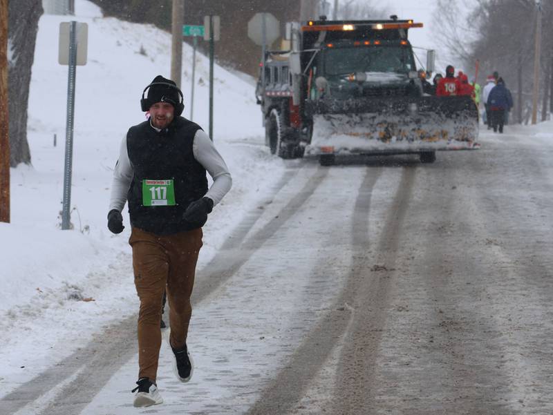 Ruan Kurkowski, runs down a hill as a snow plow turns onto Greenwood Street during the Santas on the Run 5K and one-mile walk on Saturday, Nov. 29, 2025 in Spring Valley.