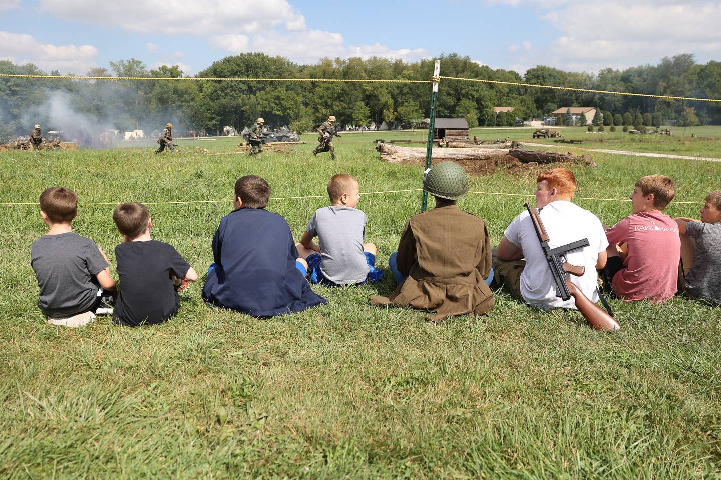 A group of kids sit as close as they can for the WWII battle re-enactment at Lockport Military History Days at Dellwood Park on Saturday, Sept. 9, 2023 in Lockport.