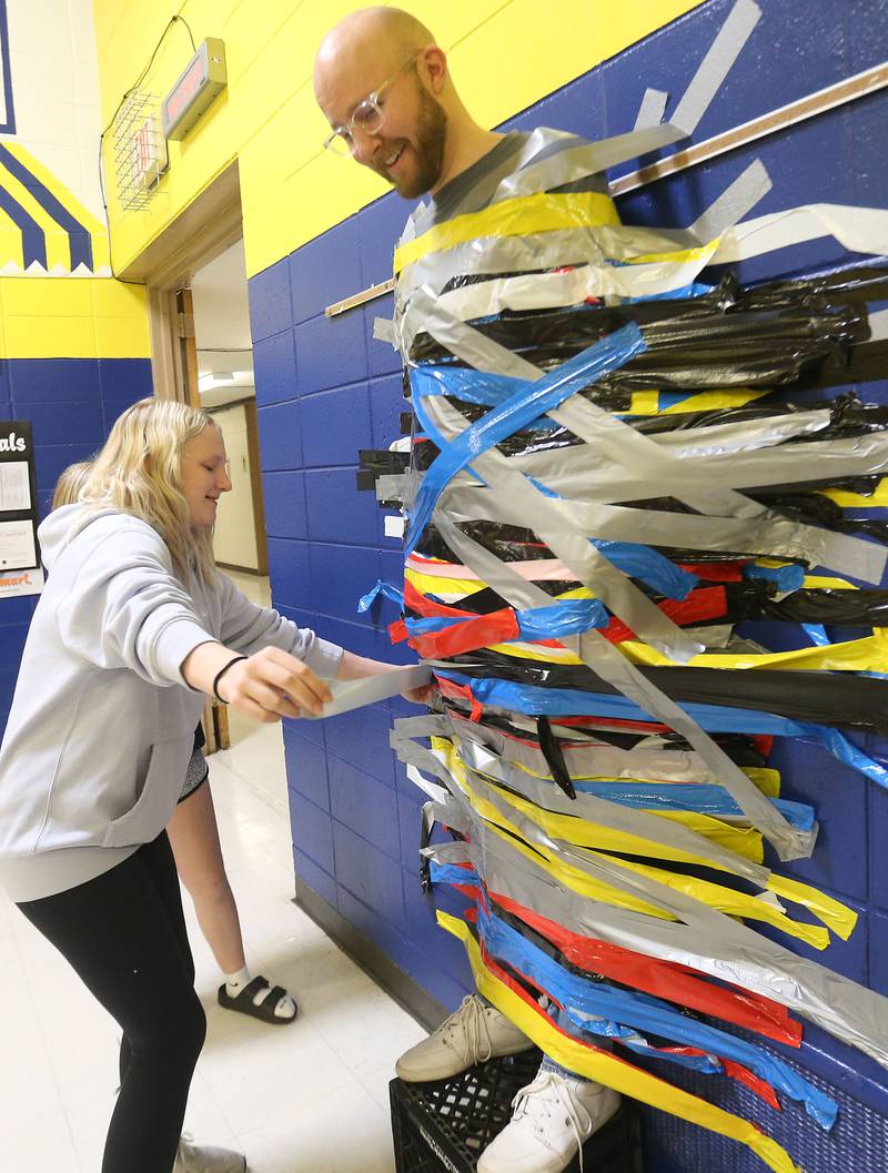 Harper Hodge places a strip of duct tape on science instructor Andrew Strickler during the inaugural Tape the Teacher fundraiser on Friday, March 20, 2026 at Logan Jr. High School in Princeton.