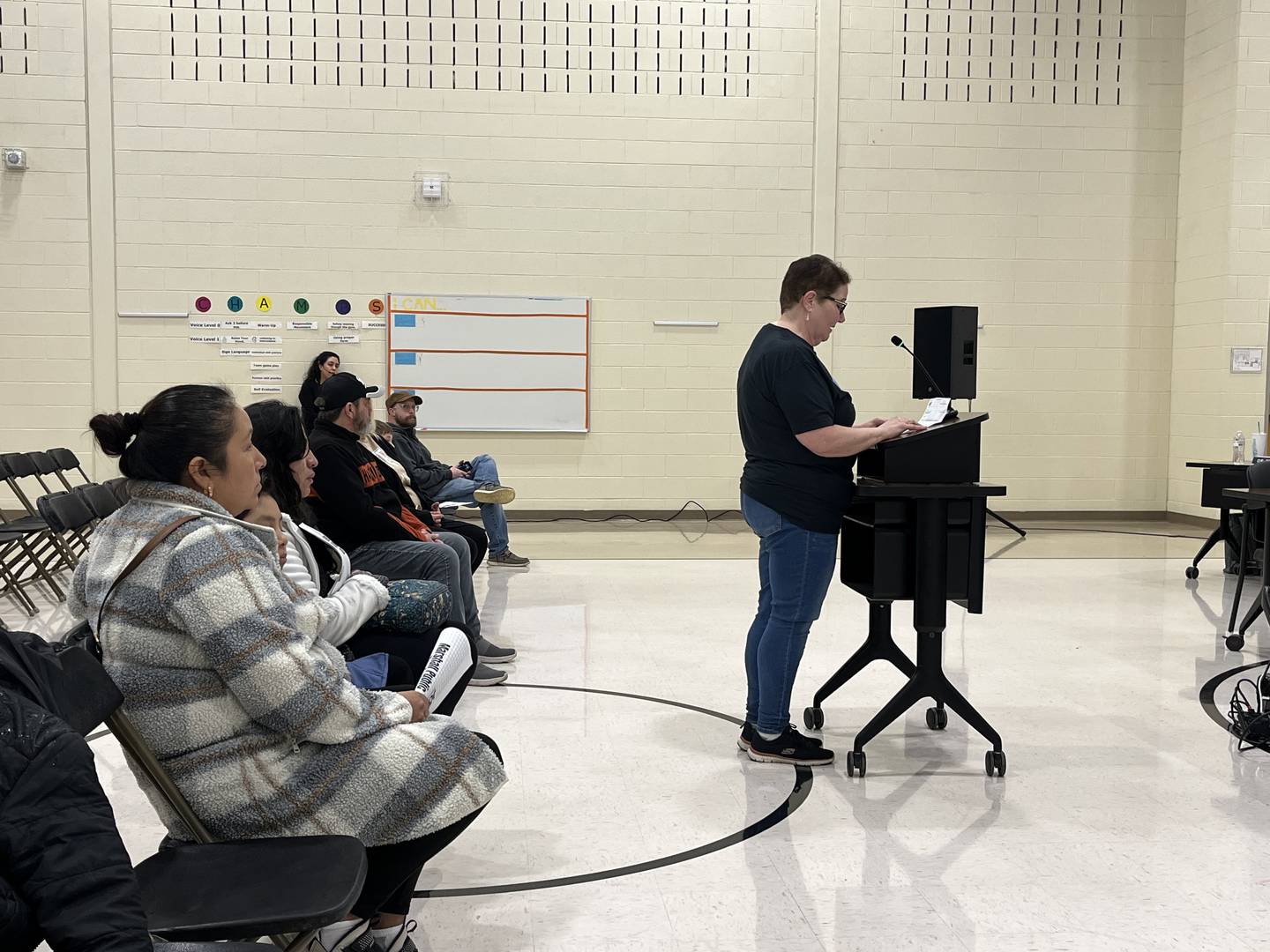 Kathy Ramirez speaks at the podium to oppose the proposed closure of A.O. Marshall Elementary School during a public hearing on Thursday, Jan. 8, 2026, at Isaac Singleton Elementary School in Joliet.