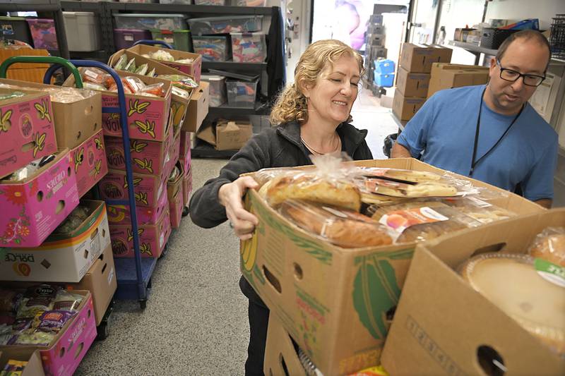 Outreach House Executive Director Catherine Lynott helps volunteer Tom Hephner unload donations at the Lombard facility on Monday, Dec. 9, 2024. Volunteer Cathy Folz checks in clients