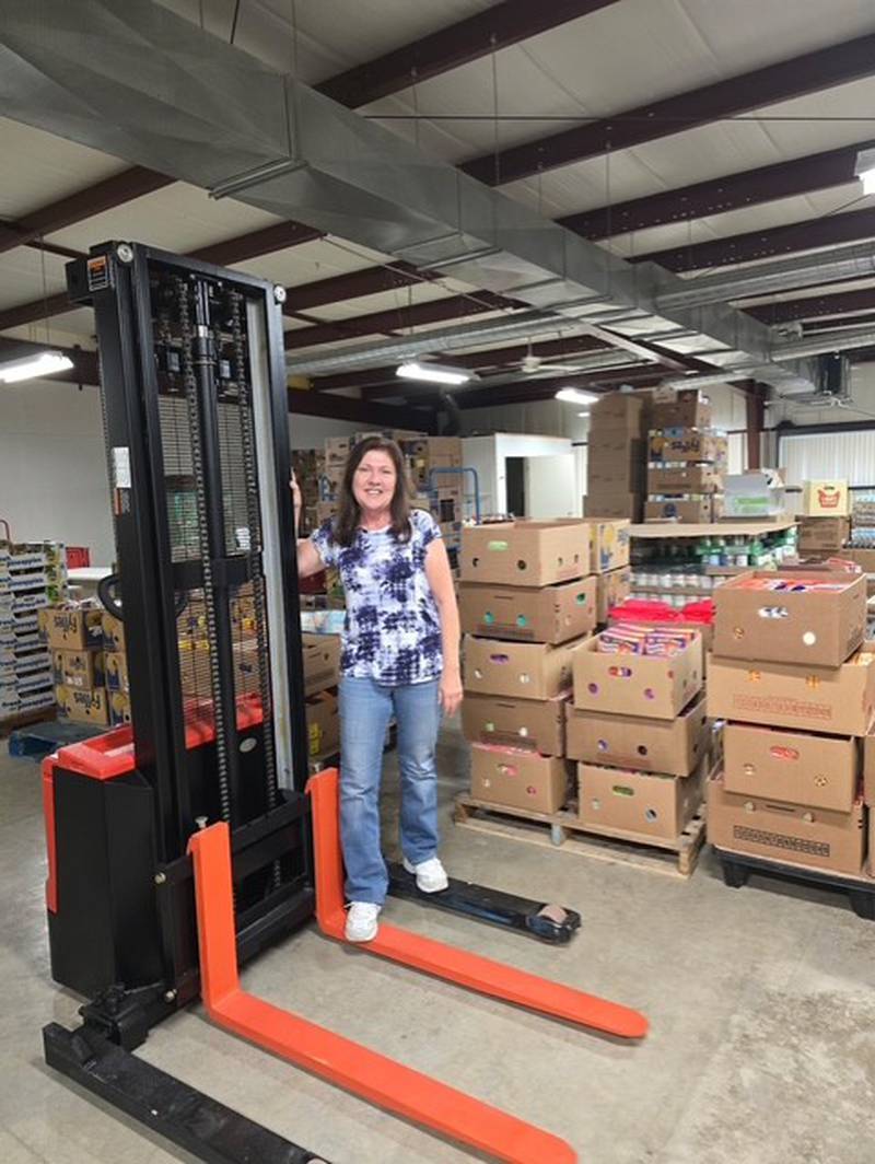 Mary Jo Credi, executive director of the Illinois Valley Food Pantry, shows off the pantry’s new electric pallet stacker, funded with an anonymous donation of more than $12,000.