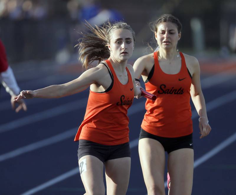 Claire Van Lue, of St. Charles East grabs the baton from Morgan Sandlund, right, in the Girls 4x800 Meter Relay during the Kane County girls track and field meet Thursday April 27, 2023 in Aurora.