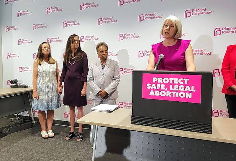 State Sen. Melinda Bush holds hands with state Rep. Kelly Cassidy during a news conference Friday afternoon with Chicago Mayor Lori Lightfoot and Planned Parenthood President and CEO Jennifer Welch where leaders called on the state to provide more money to support women from other states coming to Illinois seeking abortions.