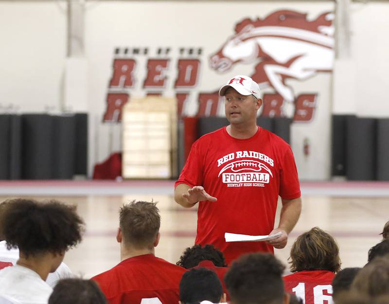 Huntley’s new coach Mike Naymola speaks to the team during the first day of football practice Monday, 8, 2022, in the Huntley High School  field house after stormy weather move practice inside.