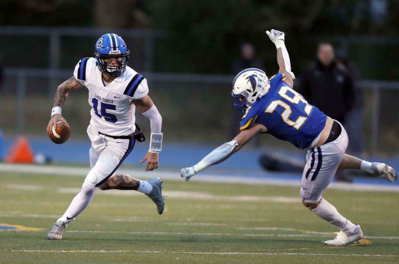 Lake Zurich's Ashton Gondeck (15) looks for an open receiver as Wheaton North's Walker Owens (29) pressures him during the second round of the IHSA playoffs Saturday November 5, 2022 in Wheaton.