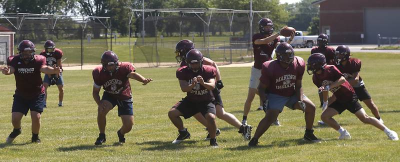 Linemen protect Marengo’s Josh Holst as they run a drill during summer football practice Monday, June 27, 2022, at Marengo Community High School in Marengo.