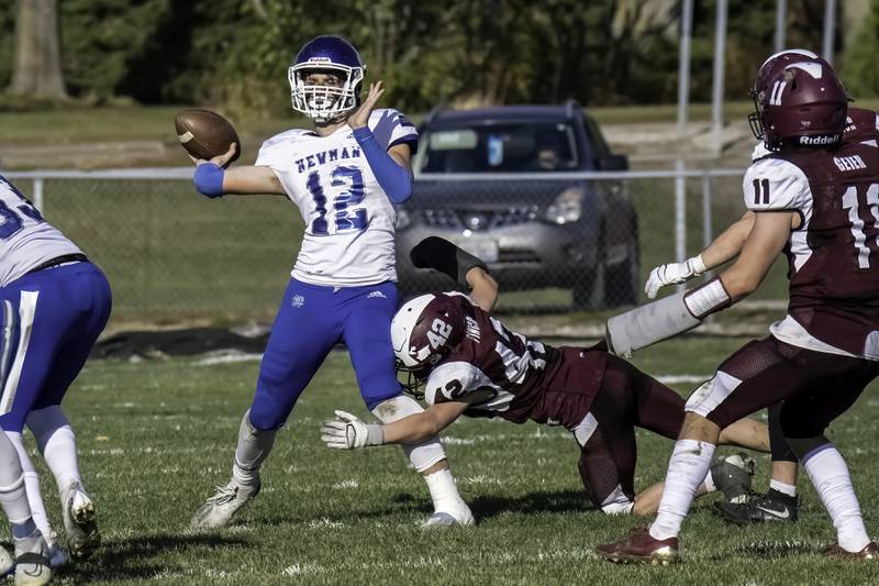 Newman quarterback JJ Castle throws a pass as he is hit by a Rockridge defender during their Class 2A first-round playoff game Saturday in Edgington.