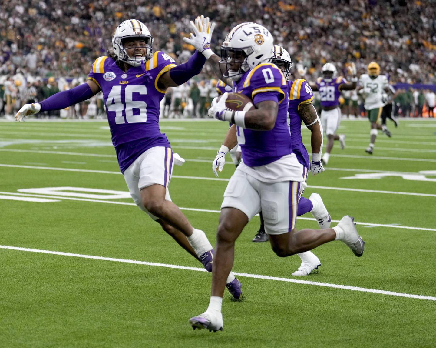 LSU linebacker Tylen Singleton, left, gives wide receiver Zavion Thomas (0) a high-five as Thomas returns a kickoff for a touchdown against Baylor during the first half of the Texas Bowl NCAA college football game Tuesday, Dec. 31, 2024, in Houston. (Brett Coomer/Houston Chronicle via AP)