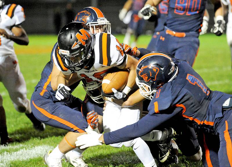 Minooka receiver Joshua Garcia is tackled between Oswego defenders Dylan Bielawski (left) and Frederick Walton (1) during the rescheduled Southwest Prairie Conference game on Saturday at Ken Pickerill Stadium in Oswego. Minooka lost, 42-7.