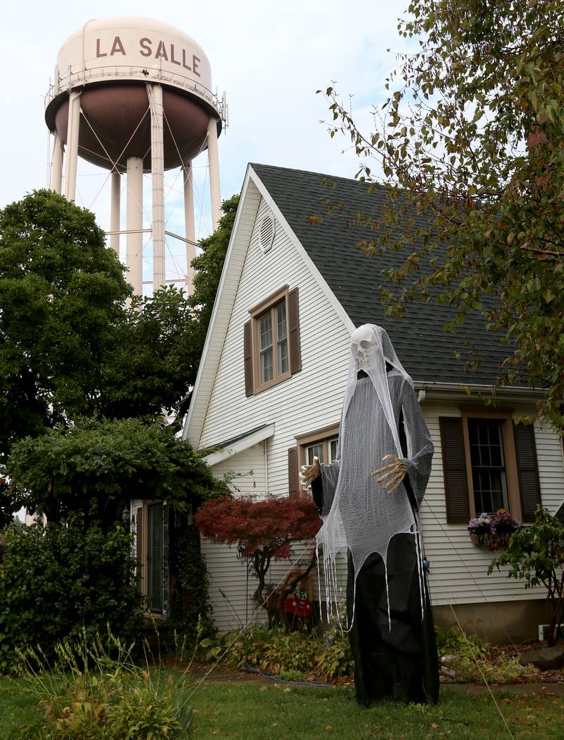 A large skeleton dressed as a ghost stands outside a home at the corner of Lincoln and Campbell Streets underneath the La Salle water tower on Thursday, Oct. 12, 2023 in La Salle.