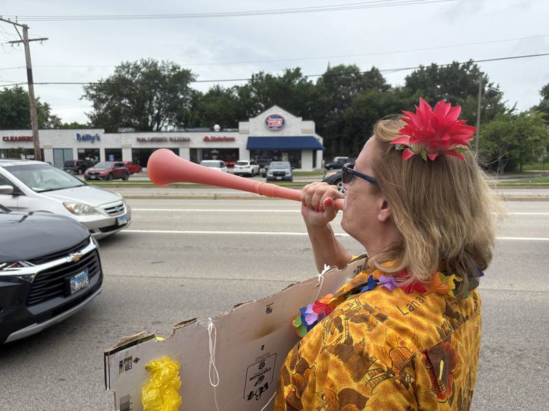Judy Newbold blows into a horn during a protest against President Trump July 26, 2025 in McHenry.