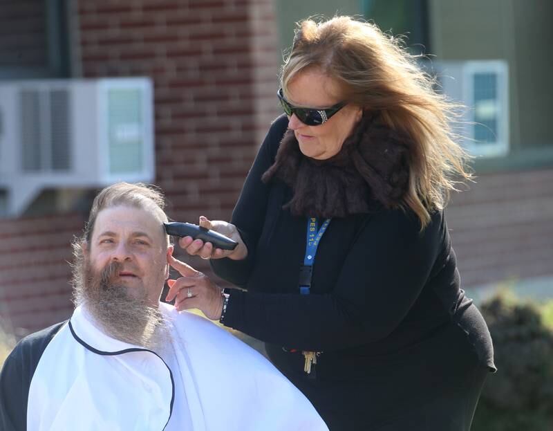 Custodian Bob Espel has his head shaved by staff member Ginger Barnes on Wednesday, May 22, 2024 at Douglas Elementary School in Princeton. Students raised more than $3.332 in the past few weeks. All proceeds will go to the new landscaping around the Douglas building, with the first round of plantings to take place with students present this Thursday, May 23. Using funds from the Preschool for All grant the school has purchased new age-appropriate playground equipment to promote physical activity, creativity and social interaction.