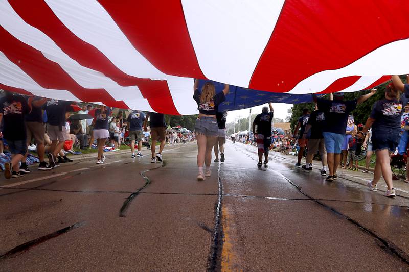 Members of the Crystal Lake Lions Club flag team carry the American Flag on Sunday, July 7, 2024, during Crystal Lake’s annual Independence Day Parade on Dole Avenue in Crystal Lake.