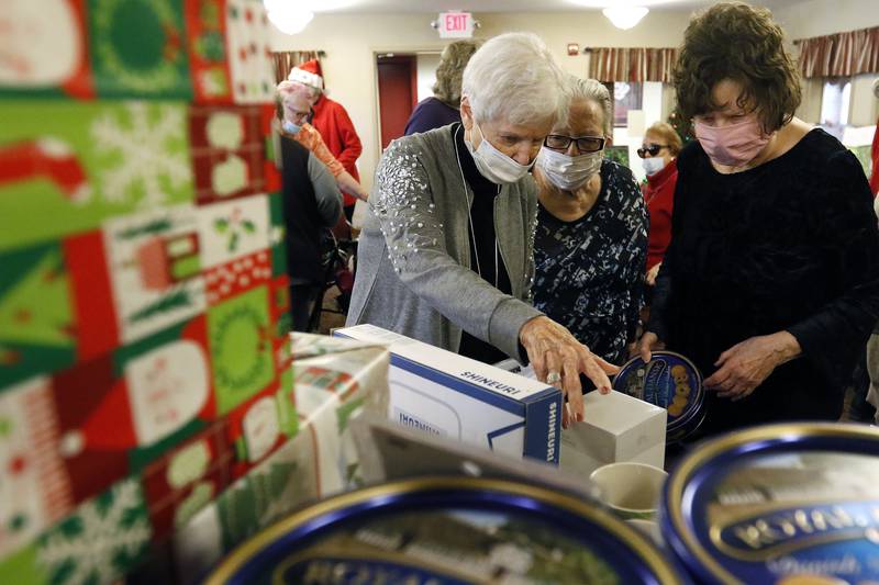 Residents look through a table piled high with gifts during an adopt-a-grandparent gift event at Gable Point Senior Housing on Wednesday, Dec. 22, 2021, in Crystal Lake.