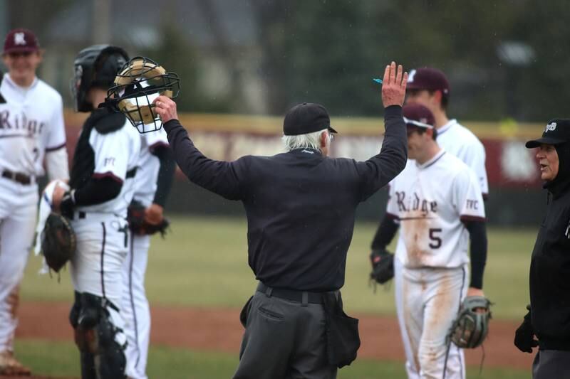 The umpiring crew suspends a game between Prairie Ridge and Jacobs in varsity baseball on Wednesday, April 9, 2025, at Prairie Ridge High School in Crystal Lake. Rains made the field unplayable.