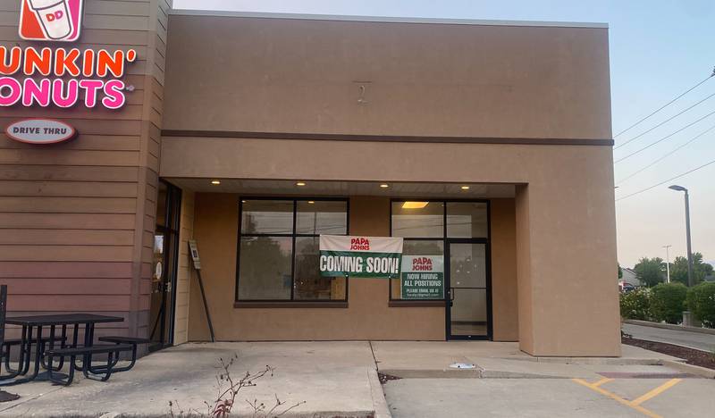 Signs indicate a Papa John's store is opening soon in Peru next to Dunkin' Donuts.
