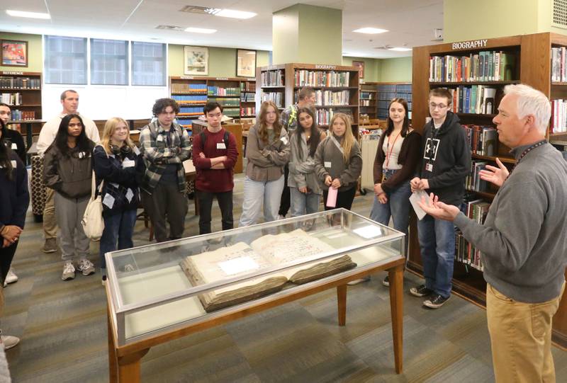 Mr. David Kelty (right) talks to Naperville Central students about an Infantry music book from the Middle Ages that is 1000 years old inside of the McCormack Memorial Library on Tuesday, April 18, 2023 at L-P High School.