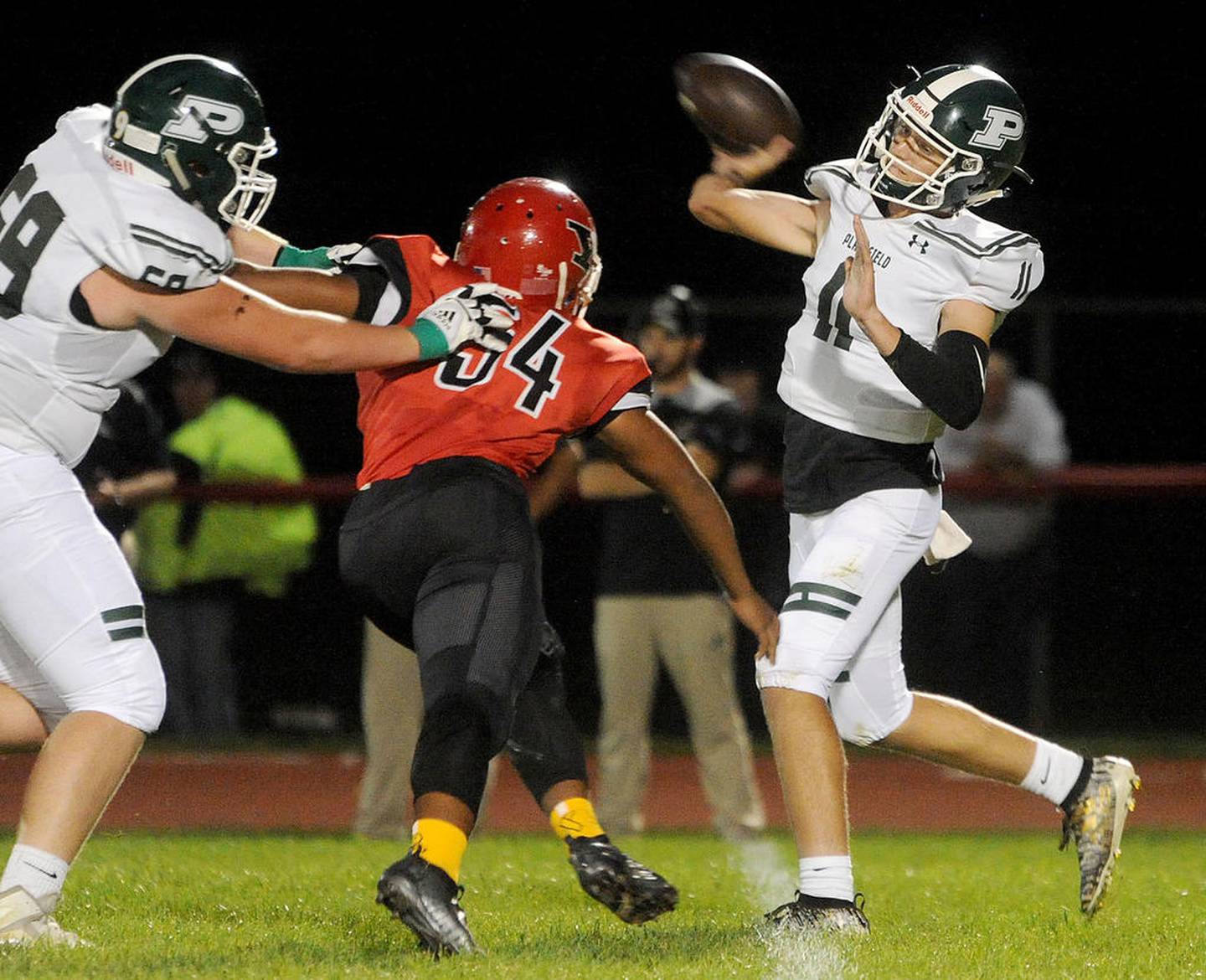 Plainfield Central quarterback Chris Leto (11) throws a pass under pressure from Yorkville defensive lineman George Alba (54) during a varsity football game at Yorkville High School on Sept. 13.
