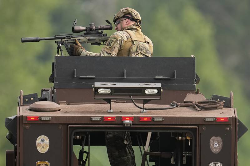 A law enforcement officer trains his rifle towards a house as the officers search for shooting suspect, Vance Boelter, Sunday, June 15, 2025, in Belle Plaine, Minn. (AP Photo/George Walker IV)