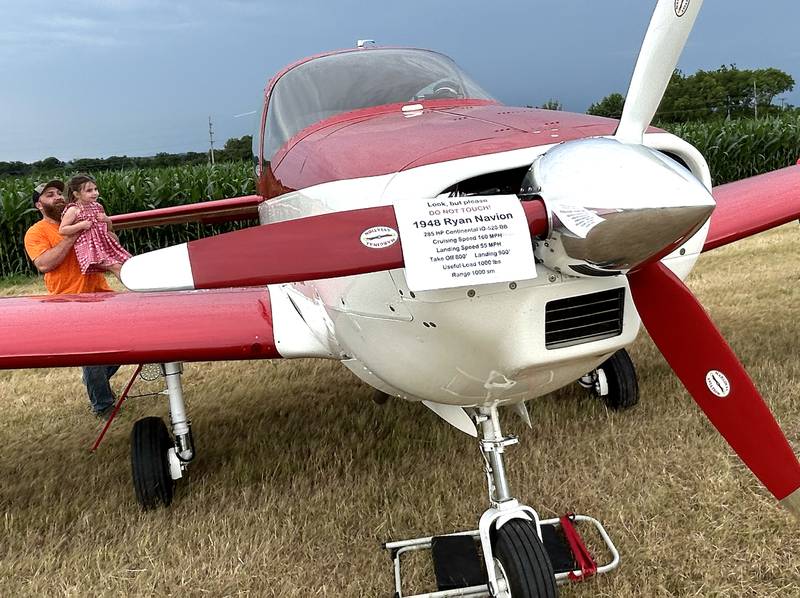 Harrison Miller, of Leaf River, lifts his daughter, Oakland, up to see inside of this 1948 Ryan Navion plane that was one of the planes on display at the Ogle County Airport's Fly in/Drive In Breakfast on Friday, July 4, 2025.