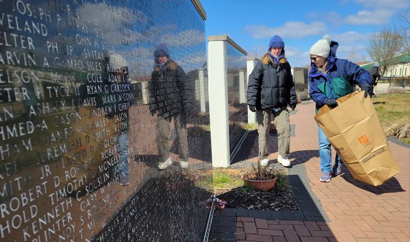 Audrey Olson (left) and her mom, Janel Olson, of the RiverGlen Christian Church gather debris from around the Middle East Conflicts Memorial Wall on Wednesday in Marseilles.