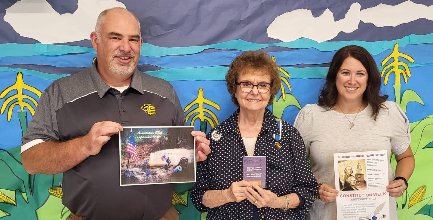 Putnam County jr. high Principal, Michael Olson, and social studies teacher, Jessica Lenkaitis, flank Chief Senachwine DAR Chapter Regent, Sharon Bittner, as they display a few of the items presented to the school for use during Constitution Week, Sept. 17-23. Ms. Bittner displays one of 75 booklets of the Constitution and Declaration of Independence which the Chief Senachwine Chapter provided to the school for use during the study of the Constitution of the United States of America.