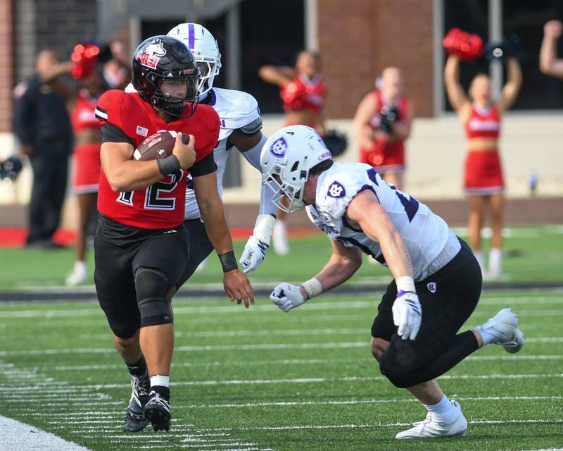 \Northern Illinois University's quarterback Jackson Proctor (12) runs the ball before being pushed out of bounds by Holy Cross’s linebacker Sam Boyer during the game on Saturday Aug. 30, 2025, held at Huskie Stadium in DeKalb.