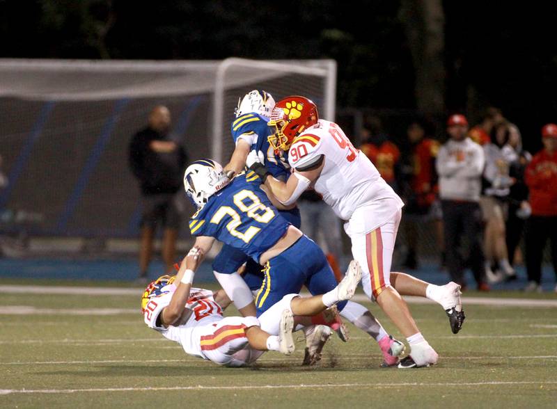 Batavia’s Chase Osborne (far left) and Gavin Pecor (far right) take down Wheaton North quarterback Nick Johnson and Max Serbick in the back field during a game on Friday, Sept. 27, 2024 at Wheaton North.