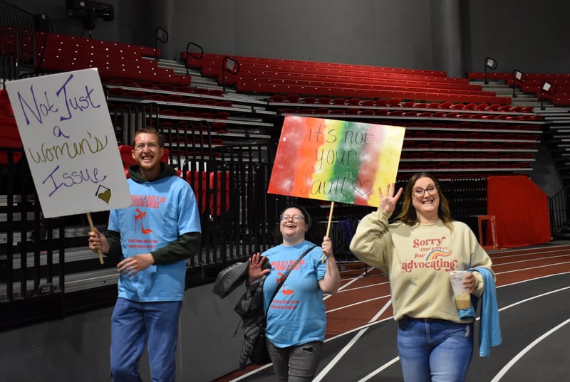 Participants hold signs and walk during Safe Passage's annual Walk A Mile in Their Shoes event on April 18, 2026, at the Northern Illinois University Convocation Center in DeKalb. The event, held to raise awareness of sexual violence and supoprt survivors, was hosted by the nonprofit as part of Sexual Assault Awareness Month.