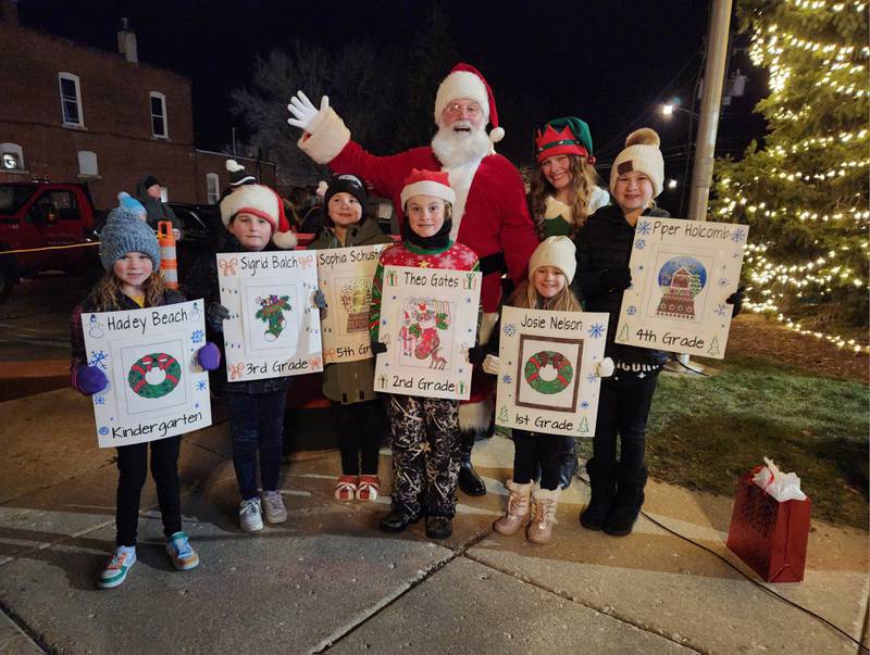 The Genoa Area Chamber of Commerce honored the coloring contest winners during its Celebrate the Season event on Friday, Dec. 6, 2024, at the tree lighting ceremony. The winners posing with Santa Claus and his elf are (from left) fifth grader Sophia Schuster;  fourth grader Piper Holcomb; third grader Sigrid Balch; second grader Theo Gates; first grader  Josie Nelson; and kindergartener Hadley Beach.