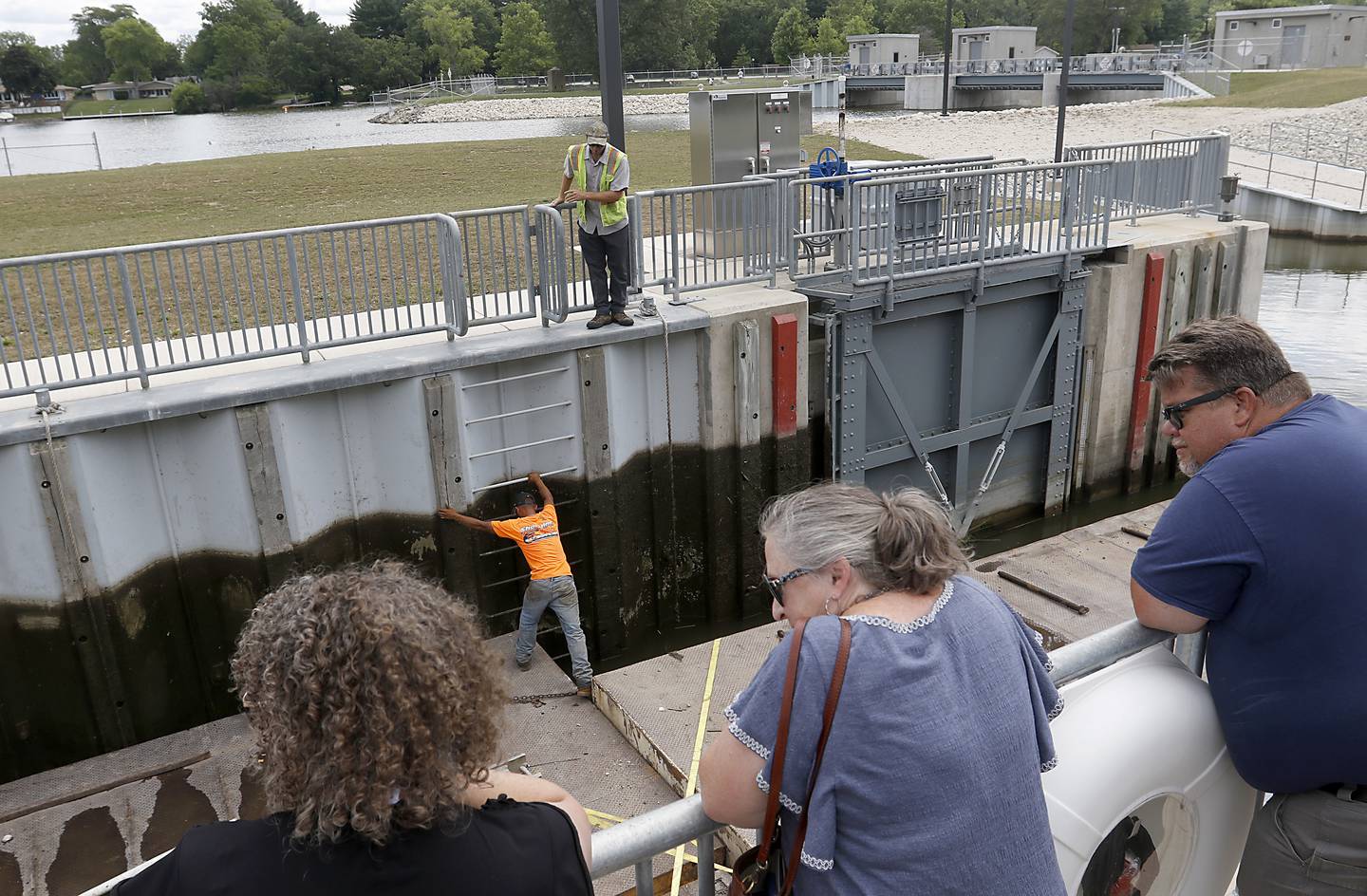 People watch as workers navigate a large barge that only has eight inches of clearance through the locks during a completion celebration of the $22 million improvement project of the Stratton Lock and Dam, 2910 State Park Road, in McHenry, on Wednesday, July 13, 2022. The dam, that is operated by Illinois Department of Natural Resources’s Office of Water Resources, to help ensure safe and efficient recreational boating on the Fox River Chain of Lakes. Close to 20,000 watercraft pass through the lock during the boating season.