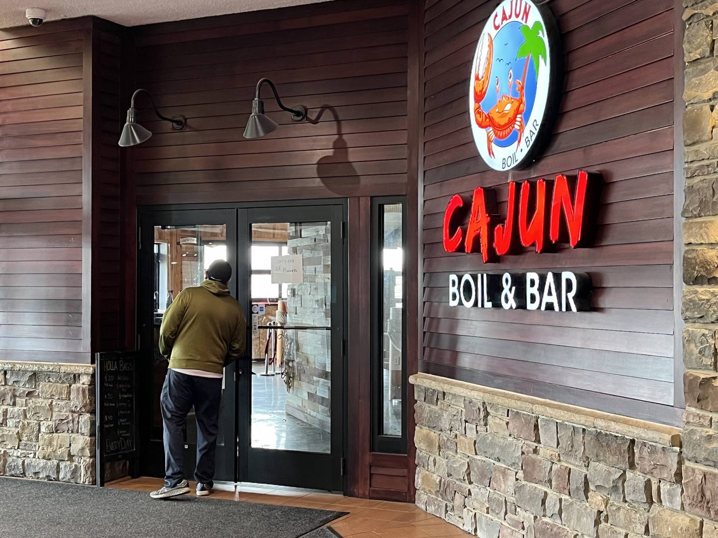 A man peering into one of the two entrances to Cajun Boil & Bar, 3340 Mall Loop Drive, Joliet, seen on Wednesday, Feb. 8, 2023.