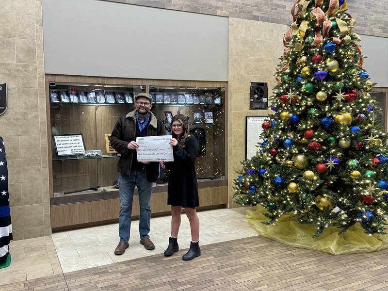 Lillian M., right, hands a check to Eric Fisher of We Care of Grundy County.