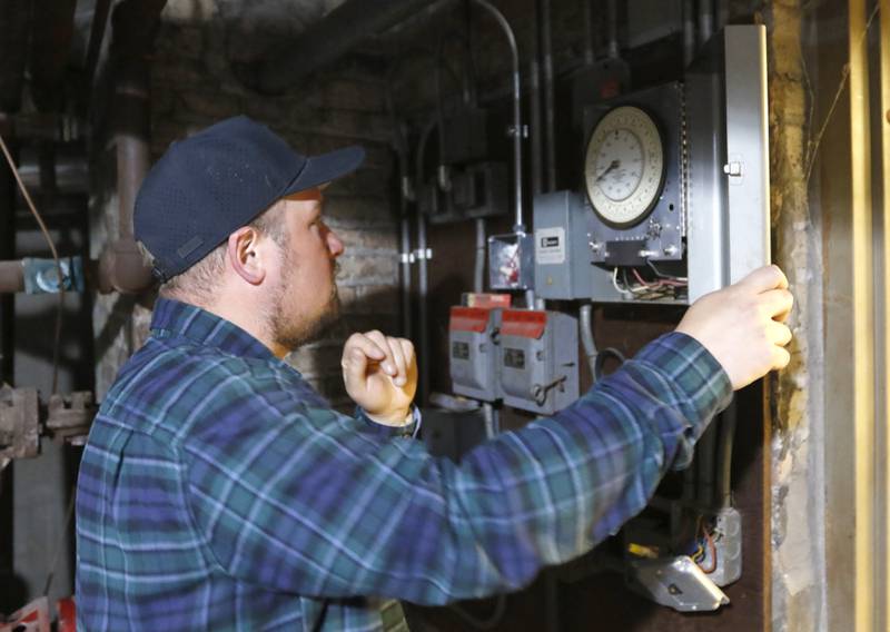 Brent Hollenberg looks at the working school bell system inside the old Ridgefield schoolhouse, at 8617 Ridgefield Road, near Crystal Lake on Wednesday, May 21, 2025. Hollenberg plans to turn the schoolhouse into a six-unit Airbnb. The building was last the home of the McHenry County Jewish Congregation.