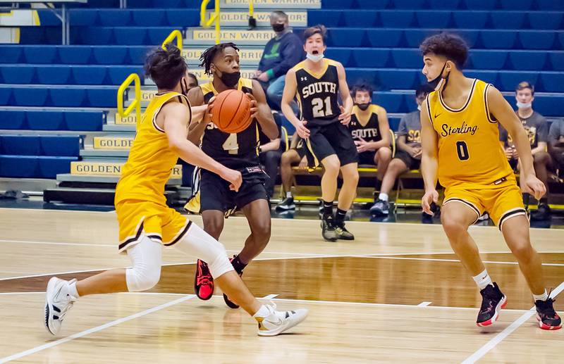 Hinsdale South's Deon Bomar (4) splits the defense against Sterling's JP Schilling and Andre Klaver (0) during their Sterling MLK tournament game Saturday evening at Musgrove Fieldhouse.