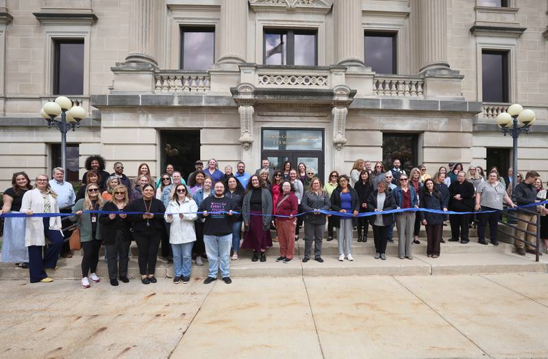 DeKalb County Courthouse officials and attendees hold a blue ribbon Wednesday, April 29, 2026, during Hands Around the Courthouse at the courthouse in Sycamore. The event was held to mark Child Abuse Prevention Month.