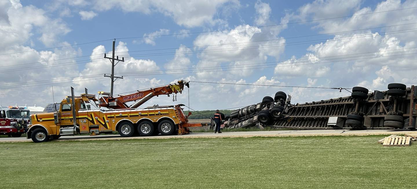 A worker with Maggio Truck Center, Rockford, hooks a cable up to the trailer of an overturned semi-tractor on Pines Road on Thursday afternoon. The accident forced the closure of a portion of Pines Road from the city limits, west to Gale Road, for several hours. The truck was hauling wooden pallets that were scattered in the north ditch. The accident remains under investigation.