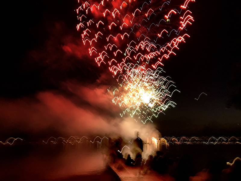 Young adults watch the fireworks show from a pier Sunday, July 2, 2023, at Crystal Lake’s Main Beach during Crystal Lake Annual Independence Day Celebration.