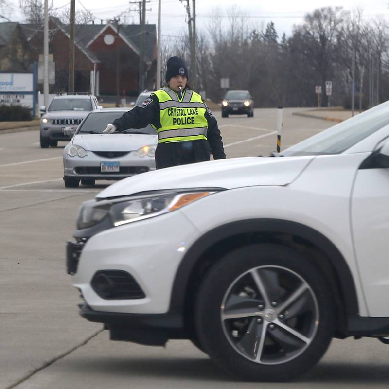 A Crystal Lake police officer directs traffic at the intersection of Route 176 and Route 14 where the traffic lights were not operating on Thursday, Feb. 23, 2023, as county residents recover from a winter storm that knocked down trees and created power outages throughout McHenry County.