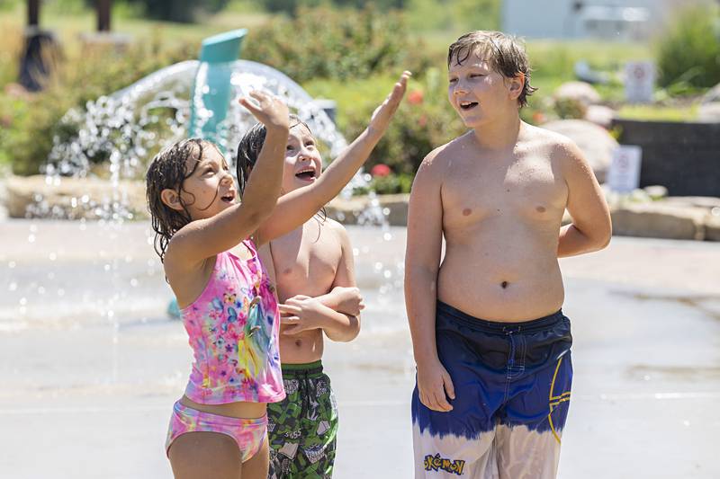 Dahlia Pels (left), 7, Alexander Rodriguez, 7, and Demitri Pels, 10, wait for the water bucket to shower the trio Thursday, July 27, 2023 at the Dixon Park District splash pad. Local splash pads around the area is one of the best ways to beat the heat in the Sauk Valley.