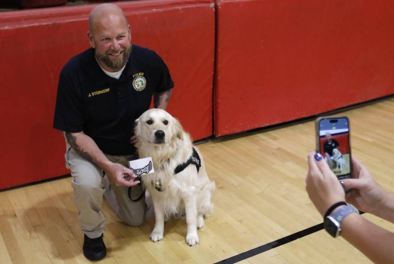 McHenry Police Department therapy dog, Oakley, and McHenry Police Department Social Services Coordinator Jason Sterwerf have their picture taken with the patch honor ing the late teacher Emily Schilf at Duker Elementary School in McHenry on Friday, Aug. 16, 2024.