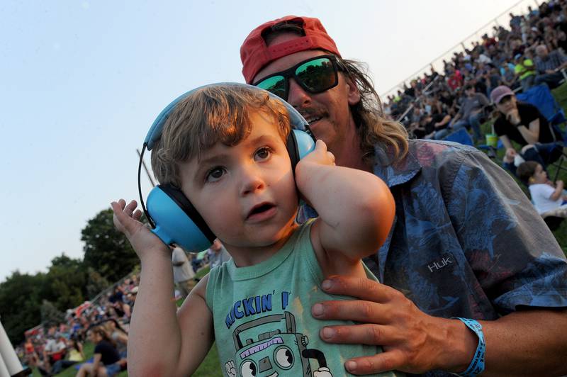 Donning ear protection, two-year-old River Copple of Morris watches the Tractor Pull competition, along with his dad Josh during the Kendall County Fair in Yorkville on Friday, Aug. 2, 2024.