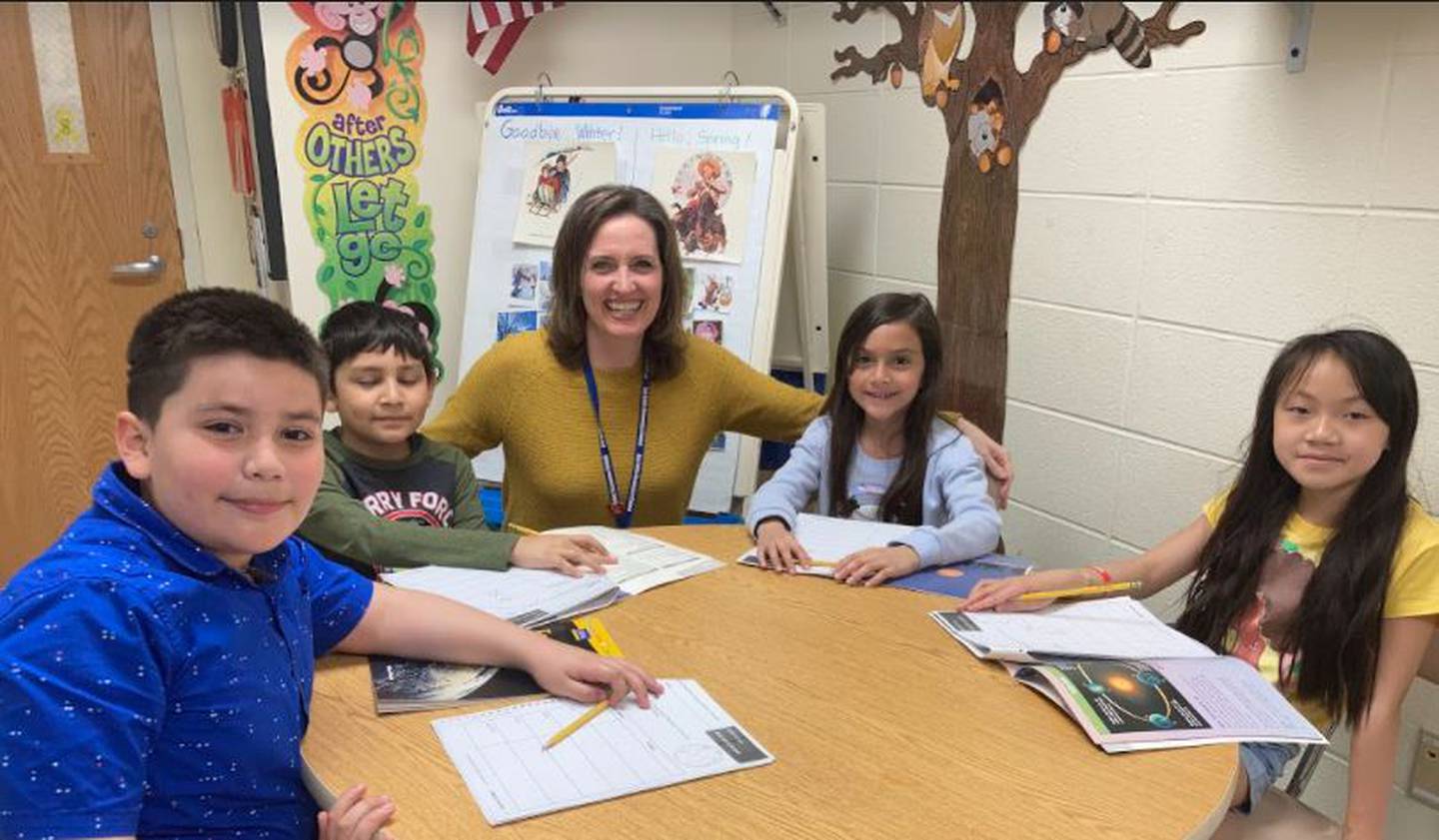 Anne Rasmusson  a teacher at Minooka School District 201's multilingual program, works with third grade students (from left) Dante, Angel, Sophia and Juma on a comprehension piece regarding space.