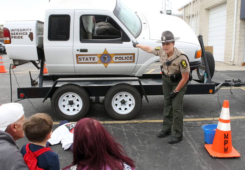 Elizabeth Clausing, trooper with the Illinois State Police, demonstrates how important it is to wear a seatbelt  if your car rolls over during the Halloween Howl at the Village of Fox Lake Police Department.
