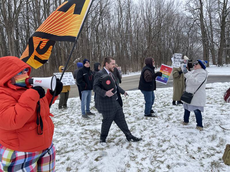Patrick Sheridan, who said he's with the group Gays Against Groomers, walks through a protest with a loudspeaker to disrupt protester chants on Saturday, Feb. 25, 2023, near the Holiday Inn in Crystal Lake.