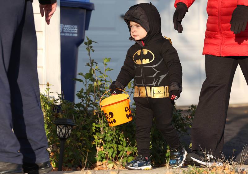 David Corral, 2, from DeKalb, walks between his parents Sam and Julie as they trick-or-treat on Halloween Tuesday, Oct. 31, 2023, in DeKalb.