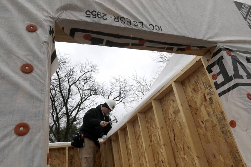 McHenry High School student David May installs weather wrap on a tiny shop being constructed Monday, May 1, 2023, at the new McHenry Riverwalk Shoppes at Miller Point Park in McHenry. McHenry High School students joined volunteers from Habitat for Humanity of McHenry County, McHenry Parks and Recreation Department staff, and contractors to build the shops at the site.