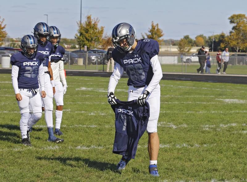 Oswego East's Alex Chapas, brother of Mark Chapas lays Mark's jersey on the field before the varsity football game between Plainfield North and Oswego East on Saturday, October 23, 2021 at Oswego East high school in Oswego, IL.