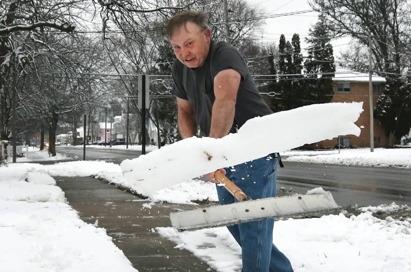 Steve Foltz doesn’t let the weather bother him as he shovels the walk in front of his house wearing a T-shirt Tuesday, Jan. 9, 2024, in DeKalb. Snow is expected to continue throughout the day with 7 to 10 inches of snow expected.